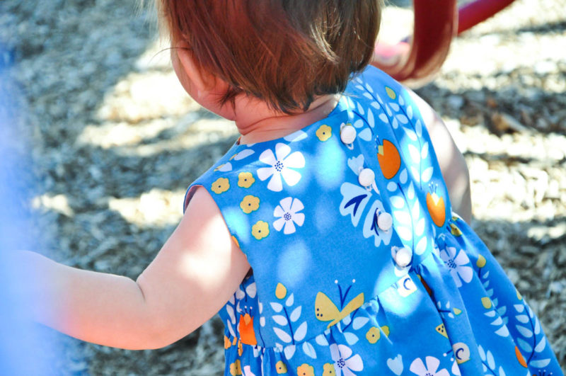 baby wearing blue dress on slide