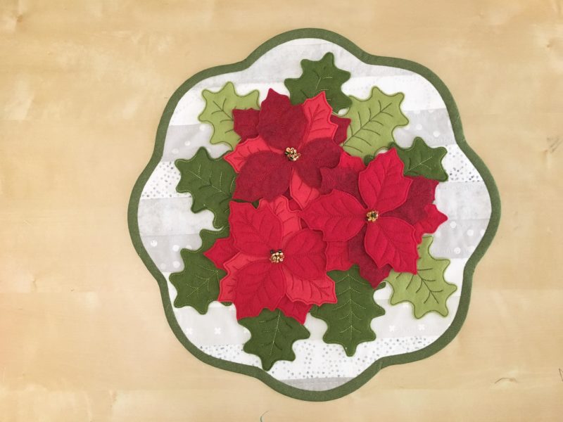 felt poinsettia and holly leaves on qhite background